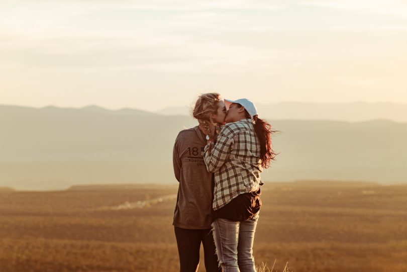 two women kiss with landscape sandy background
