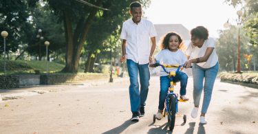parents teaching kid to ride bike