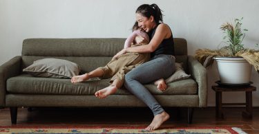 mom and child hugging and laughing on couch